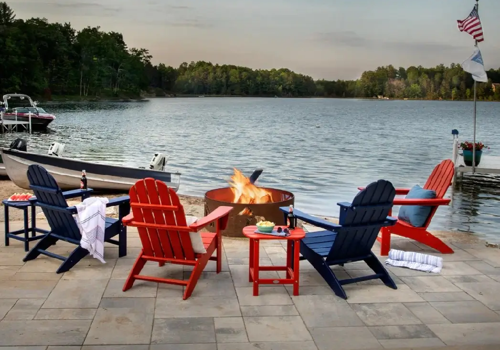Lakeside patio featuring red and blue Adirondack chairs gathered around a fire pit for evening relaxation and socializing.